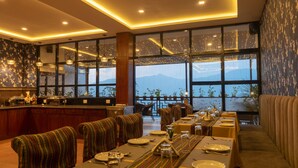 A dining area with a view of mountains, large windows, and a bar counter.
