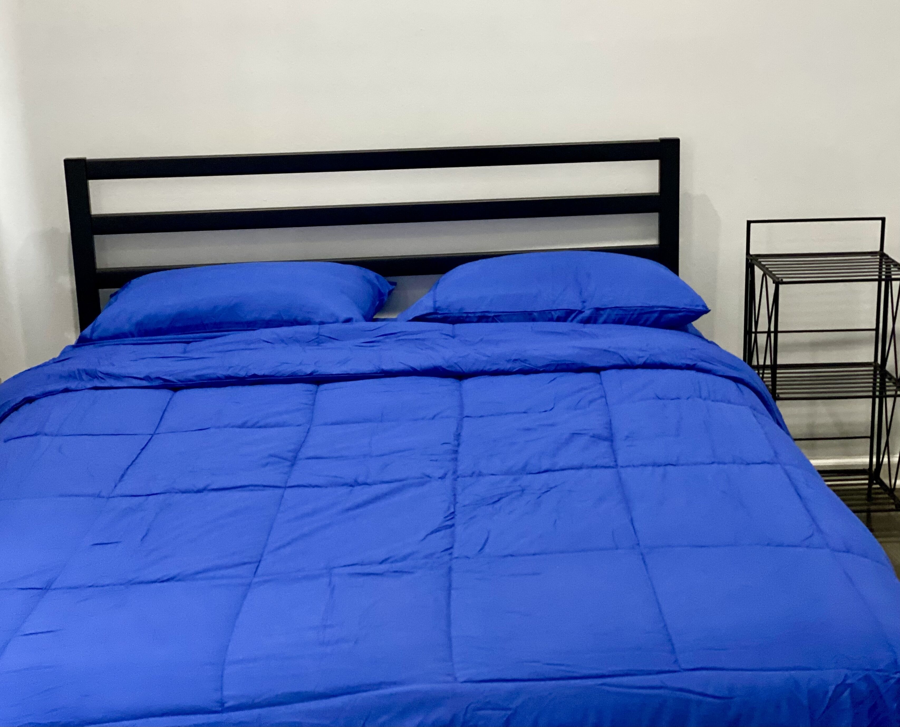 Ein Bett mit schwarzem Kopfteil und blauer Bettwäsche.