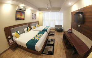 Habitación de hotel con dos camas, televisor, escritorio y ventana con cortinas.