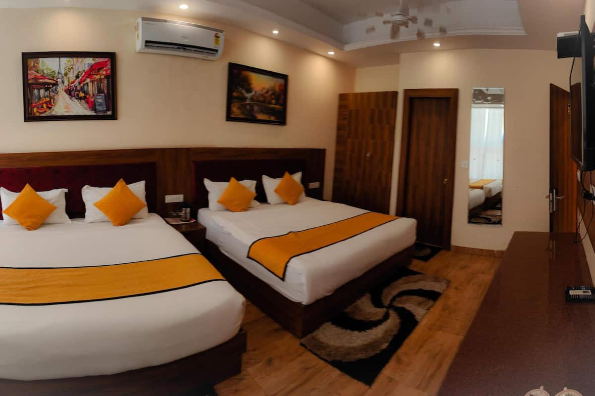 A hotel room with two beds, a TV, and artwork on the walls.