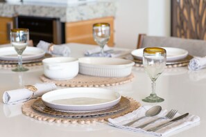 A dining table set with white plates, bowls, and glasses, accompanied by a napkin and cutlery. - Mexico Eldorado 106 (Ajijic)