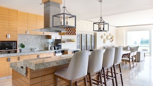 Una cocina moderna con encimeras de granito, armarios de madera y taburetes de bar.