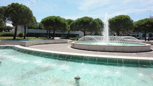 Une fontaine circulaire avec des jets d’eau au centre, entourée d’un bassin.