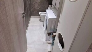 Et moderne badeværelse med en indbygget vaskemaskine, toilet og håndvask.