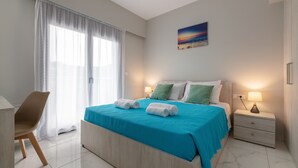 Ein Schlafzimmer mit Bett, Stuhl, Nachttisch und einem Bild an der Wand.