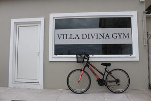 Una bicicleta estacionada frente a un edificio con un letrero que dice "VILLA DIVINA GYM".