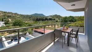 Ein Balkon mit Tisch und Stühlen mit Blick auf eine hügelige Landschaft mit Gebäuden.