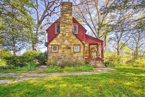 A stone house with a red roof and a chimney, surrounded by greenery and trees. - Dreamy Homestead Escape: Patio, Ranch On-Site (Crossville)