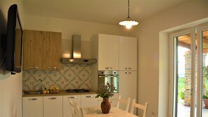 Een moderne keuken met witte kasten, een fornuis en een eethoek met een tafel en stoelen.