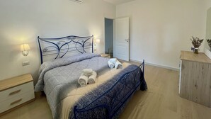 Een slaapkamer met een bed, nachtlampen, een nachtkastje, een dressoir en een plafondventilator.