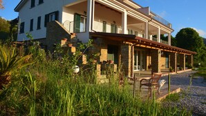 Een herenhuis met twee verdiepingen, een stenen gevel, een balkon en een overdekte veranda.