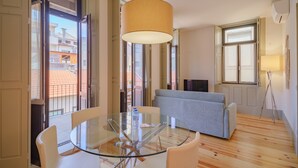 A modern living room with a glass table, a grey sofa, and a hanging lamp. - Feel Porto Matosinhos Ocean Flat III (Matosinhos)