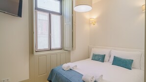 A bedroom with a bed, a window, a wall-mounted TV, and a wall light. - Feel Porto Matosinhos Ocean Flat III (Matosinhos)