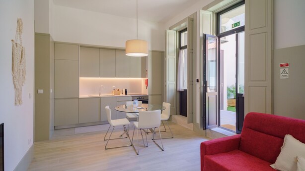 Un interior moderno con comedor, cocina y un sofá rojo.