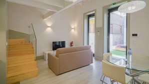 Un interior moderno con una escalera, un sofá, una mesa de vidrio y un televisor.