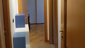 A hallway with wooden doors, a white and blue furniture piece, and a wooden floor. - Green view penthouse with beautiful terrace and playground (Lazio)