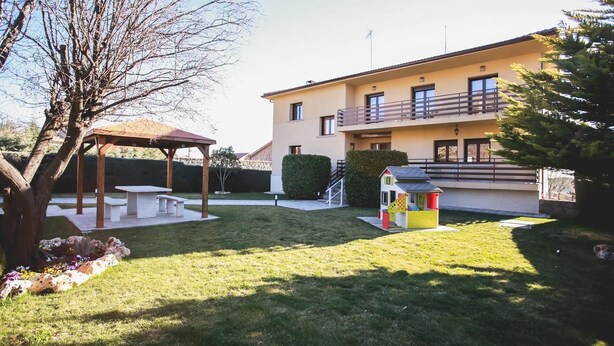 Un bâtiment à deux étages doté d’un balcon, d’une terrasse couverte et d’une petite maison de jeu.