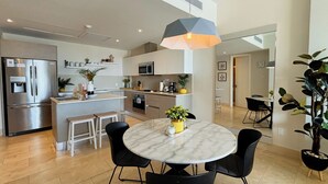 Una cucina moderna con isola centrale, elettrodomestici in acciaio inossidabile e zona pranzo con tavolo in marmo e sedie nere.