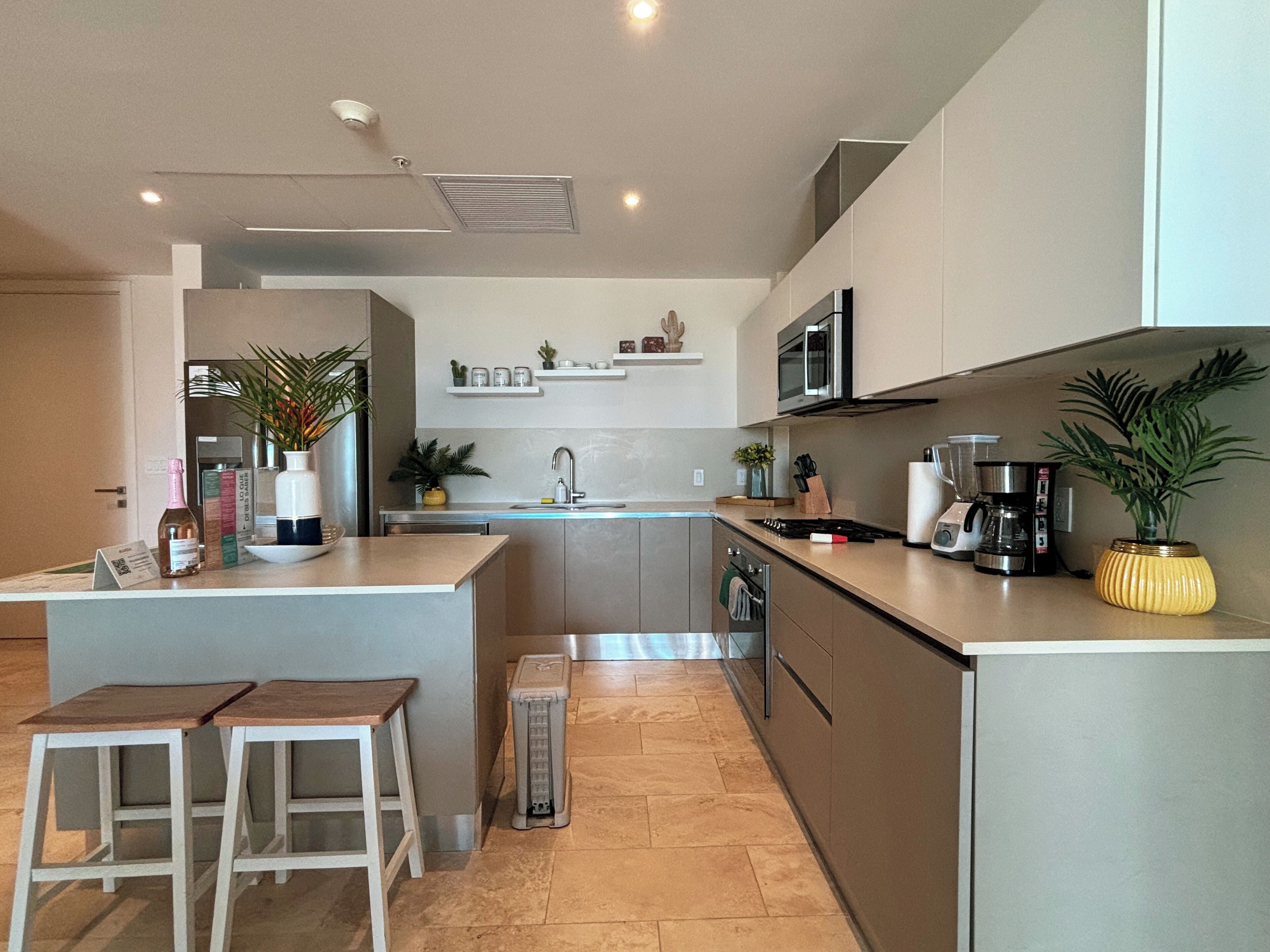 A modern kitchen with a central island, bar stools, and a built-in oven.