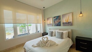 Una camera da letto con un letto grande, un ventilatore a soffitto e opere d'arte alle pareti.
