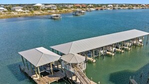 A waterfront property with a dock, covered seating areas, and a boat. - Jubilee Landing 303 | Boaters Welcome | Outdoor Pool | My Beach Getaways (Orange Beach)