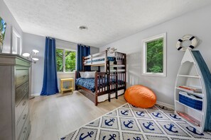 Cozy nautical-themed room with a bunk bed, dresser, and bookshelf, perfect for kids to play and read.