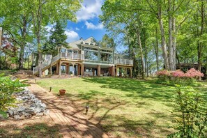 Enjoy the serene surroundings from the two-story house's expansive balcony, overlooking mature trees and a well-manicured lawn.