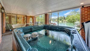 A hot tub with a view of a lake, surrounded by brick walls and large windows. - Lake Grace - Lakefront, Private Dock & Hot Tub (Moneta)