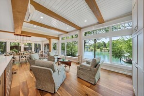 Relax in a spacious living area with a high ceiling and large windows offering serene lake views.