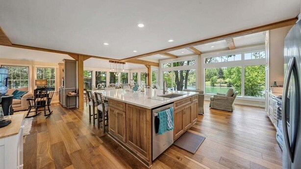 A spacious kitchen with a large island, wooden flooring, and large windows offering views of the outdoors. - Lake Grace - Lakefront, Private Dock & Hot Tub (Moneta)