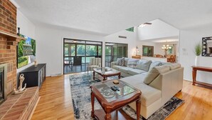 Uma sala de estar espaçosa com lareira, um sofá grande e uma mesa de centro de vidro.