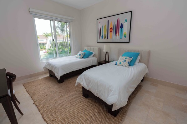 A hotel room with two beds, a large window, and a wall-mounted artwork.