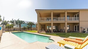 A two-story building with a pool, outdoor seating, and a well-maintained lawn.