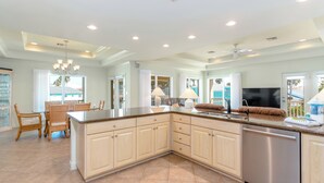 A spacious kitchen with a large island, built-in appliances, and a dining area with wicker chairs.