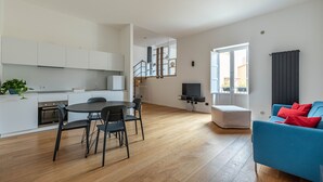 Un appartamento moderno con cucina, sala da pranzo, soggiorno e una scala che conduce a un piano superiore.