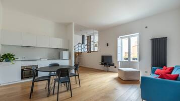 Een modern appartement met keuken, eethoek, woonkamer en een trap naar een verdieping.