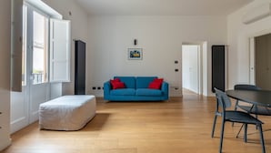 Un soggiorno ampio con un divano blu, un poggiapiedi e un tavolo da pranzo con sedie.