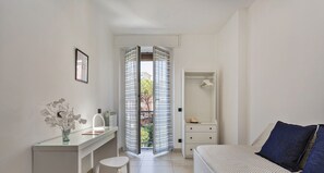 Une chambre à coucher avec un lit, un bureau avec une chaise, un radiateur et une fenêtre avec des rideaux.