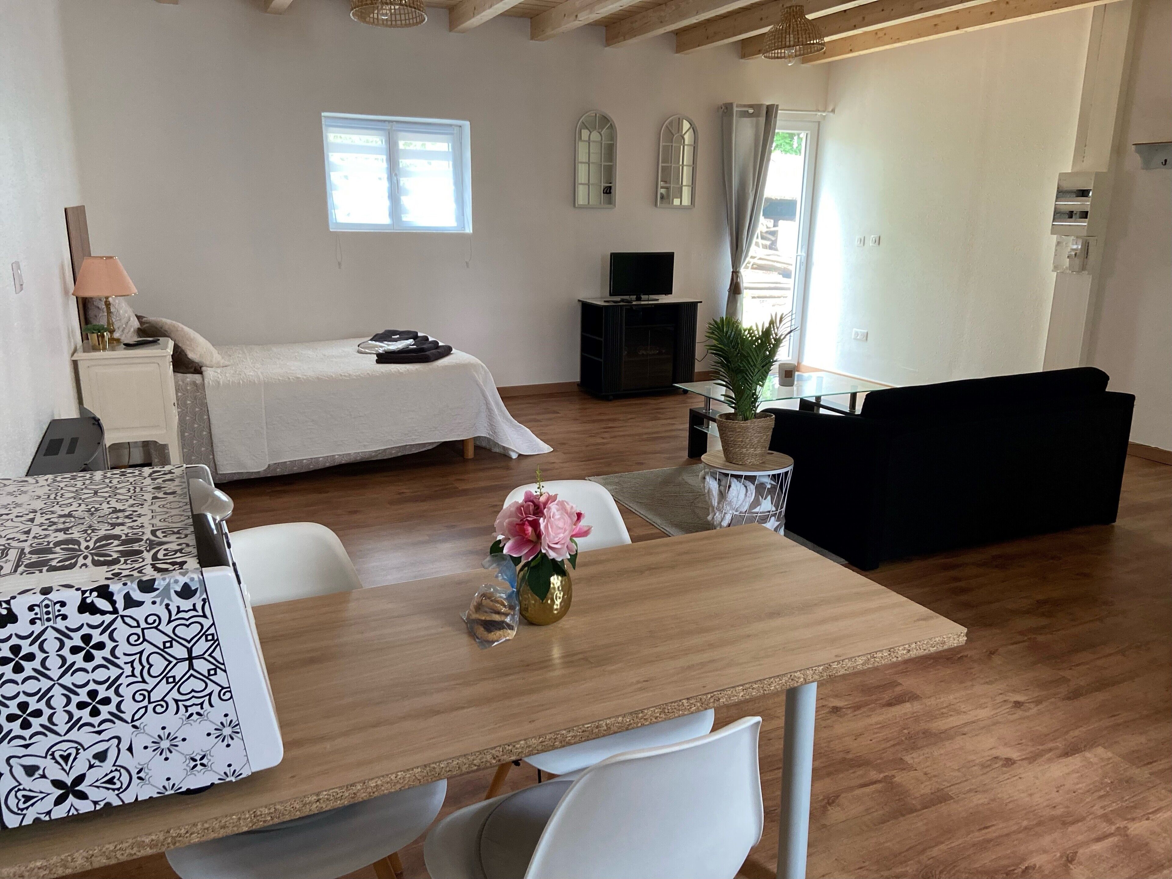 Ein modernes Wohnzimmer mit Bett, Essbereich und Fernseher.