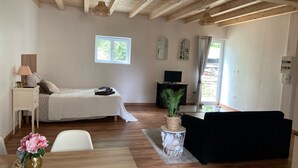 Un dormitorio con cama, mesita de noche, lámpara y ventana.