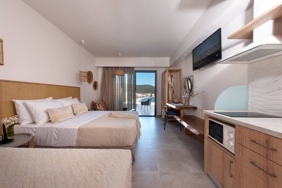 A modern hotel room with a large bed, a desk, a television, and a view of the outdoors.