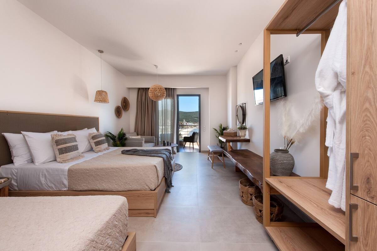 A modern hotel room with two beds, a desk, and a view of the outdoors.