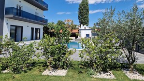 A modern two-story building with a swimming pool, surrounded by well-maintained greenery and a clear blue sky. - Luxury villa with private swimming pool (Zmijavci)