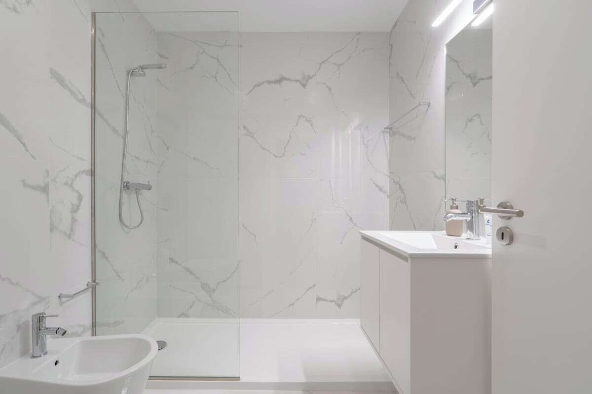 A modern bathroom with a glass shower enclosure, a freestanding sink, and a vanity with a mirror.