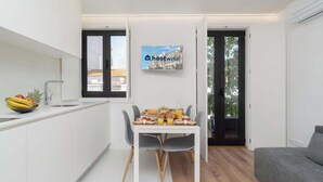 Une cuisine moderne avec une table à manger mise pour le petit-déjeuner, un saladier rempli de fruits et un tableau accroché au mur.