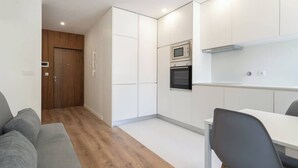 Une cuisine moderne avec des meubles blancs, un four encastré et un four à micro-ondes.