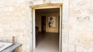 Corredor de paredes de pedra que leva a um quarto com uma moldura na parede.