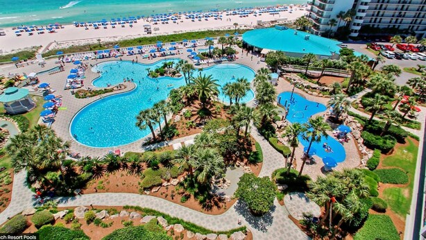 Un resort con varias piscinas, playa y estacionamiento.