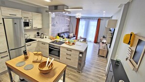 Una cucina moderna con isola centrale, elettrodomestici in acciaio inossidabile e zona pranzo con tavolo in legno.