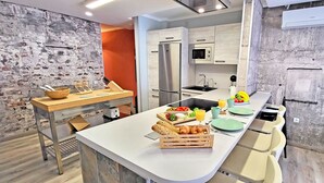 Una cucina moderna con isola centrale, elettrodomestici integrati e una parete in mattoni rustici.